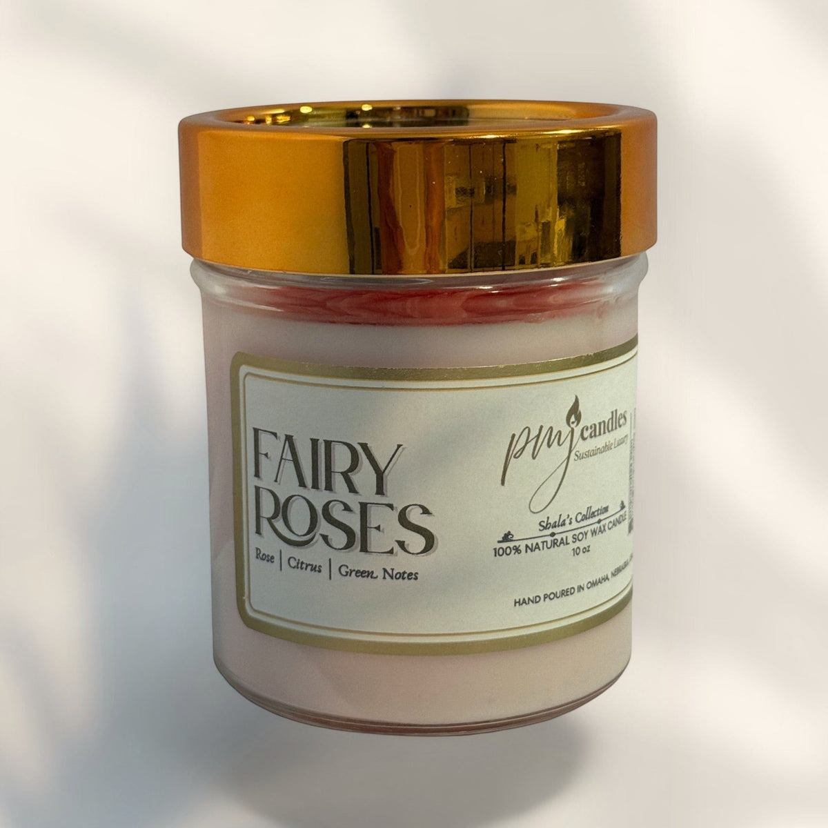 PMJ Candles Fairy Roses soy wax candle in a glass jar with a metallic gold lid and a cream-colored label.