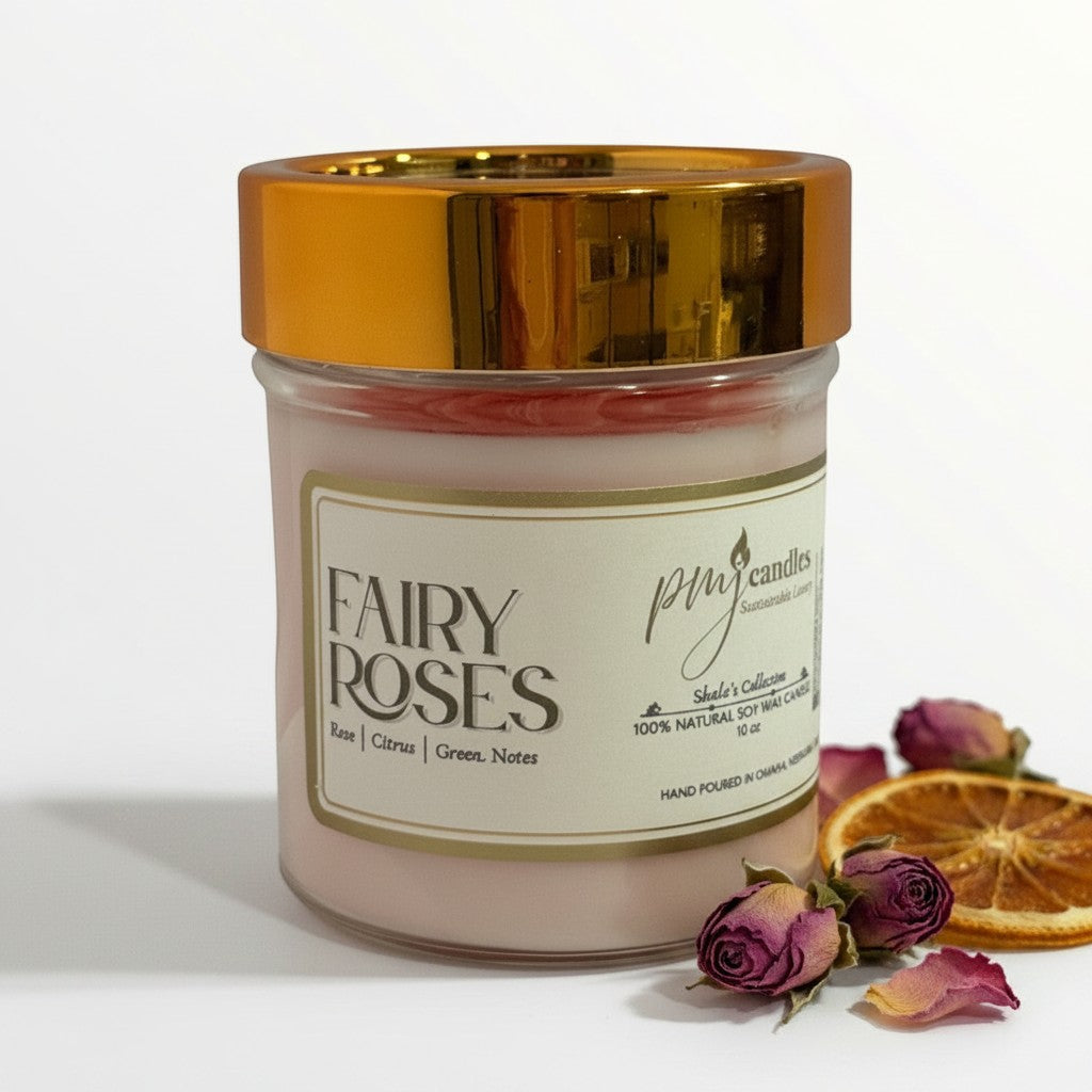 PMJ Candles Fairy Roses soy candle in a glass jar with a gold lid, featuring dried rosebuds and citrus slices.