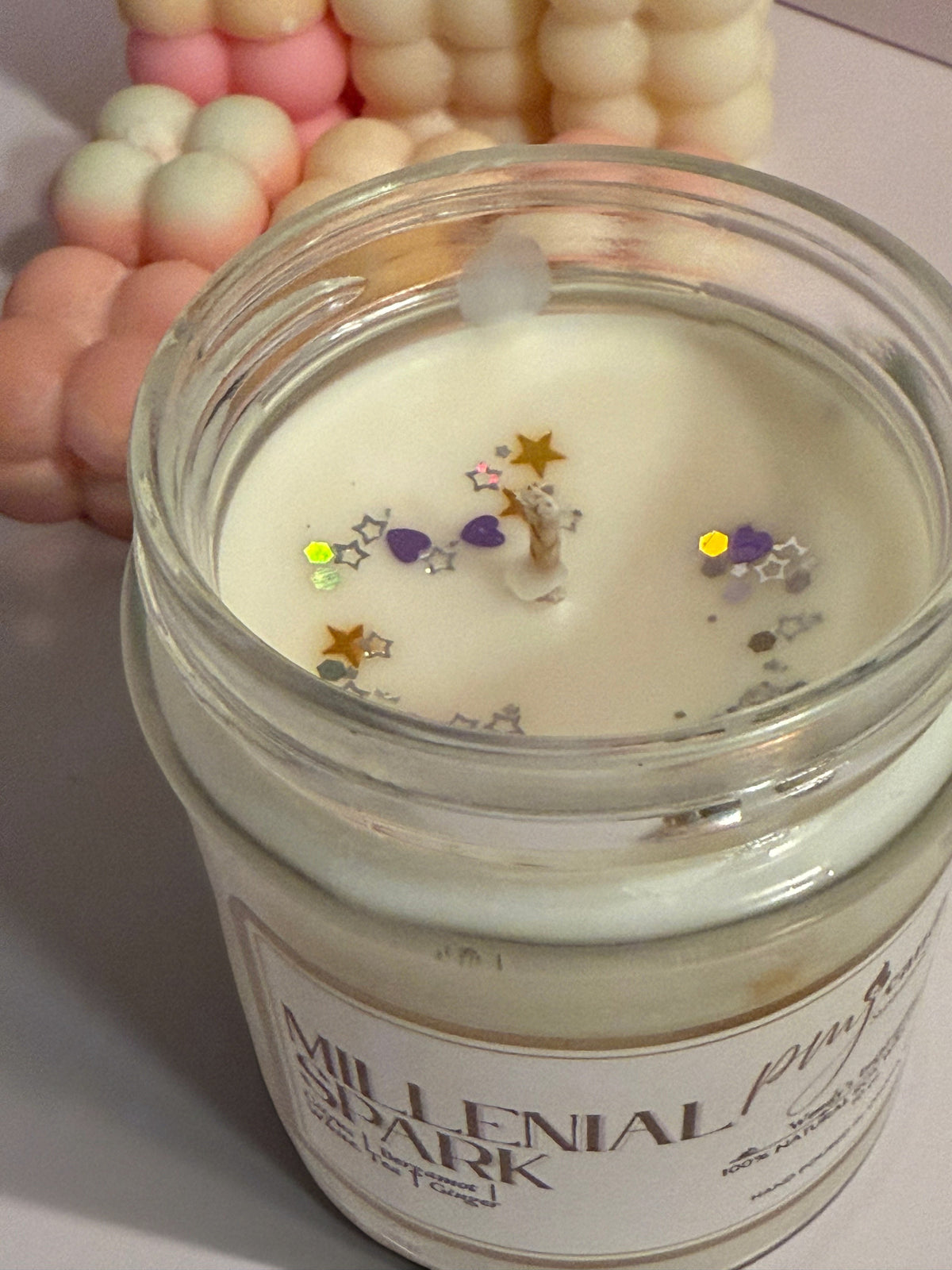 PMJ Candles Millennial Spark soy wax candle in a glass jar topped with decorative star and heart glitter
