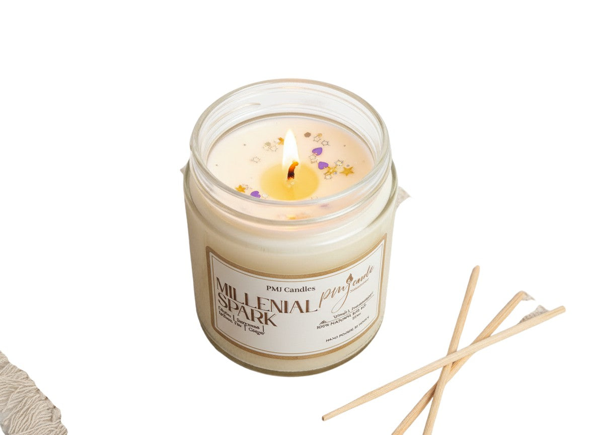 PMJ Candles Millennial Spark soy wax candle in a glass jar with a lit wick and decorative star and heart sprinkles.