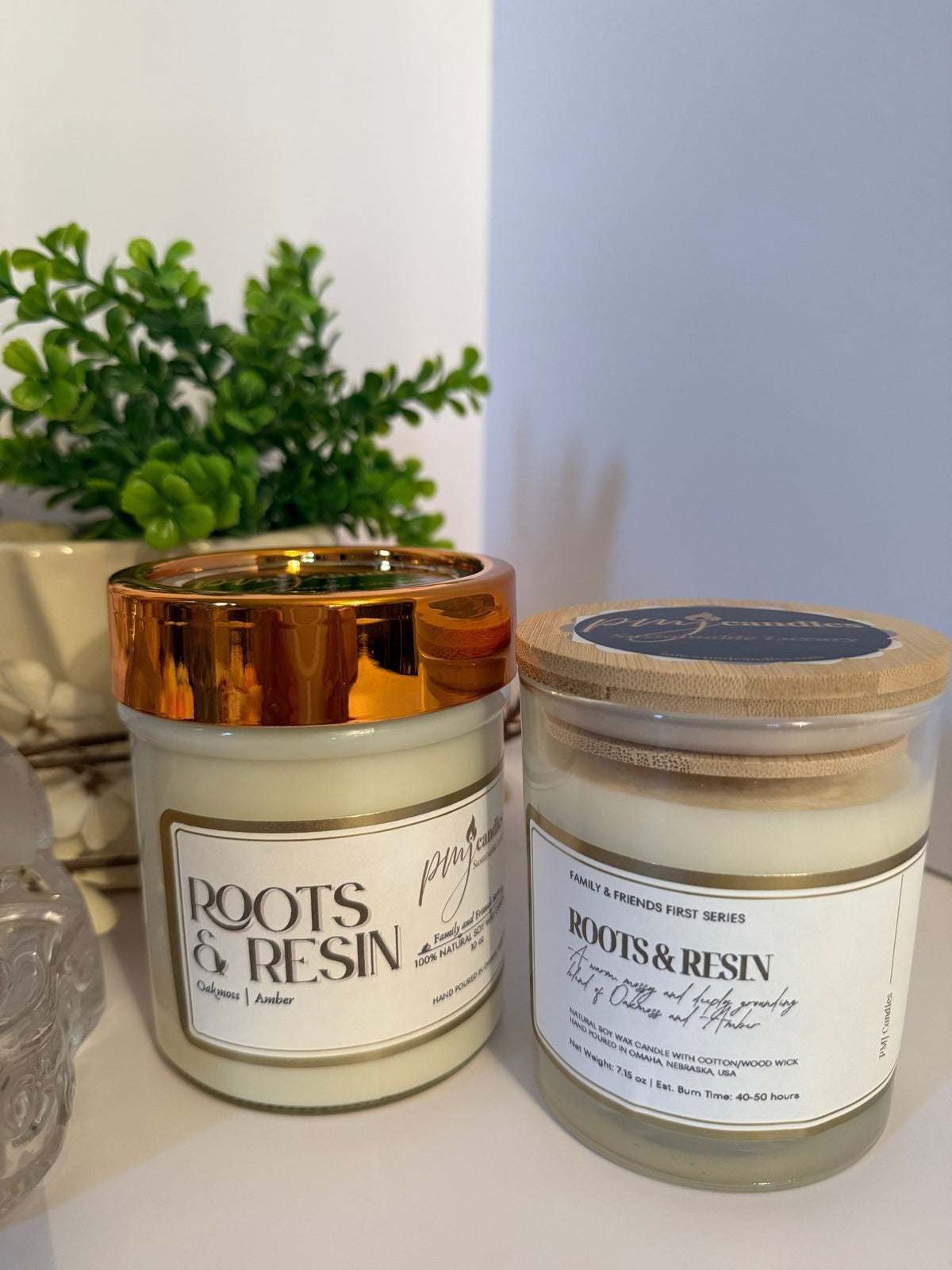 PMJ Candles Roots and Resin soy wax candles with gold and wood lids, featuring earthy cedarwood and amber scents.