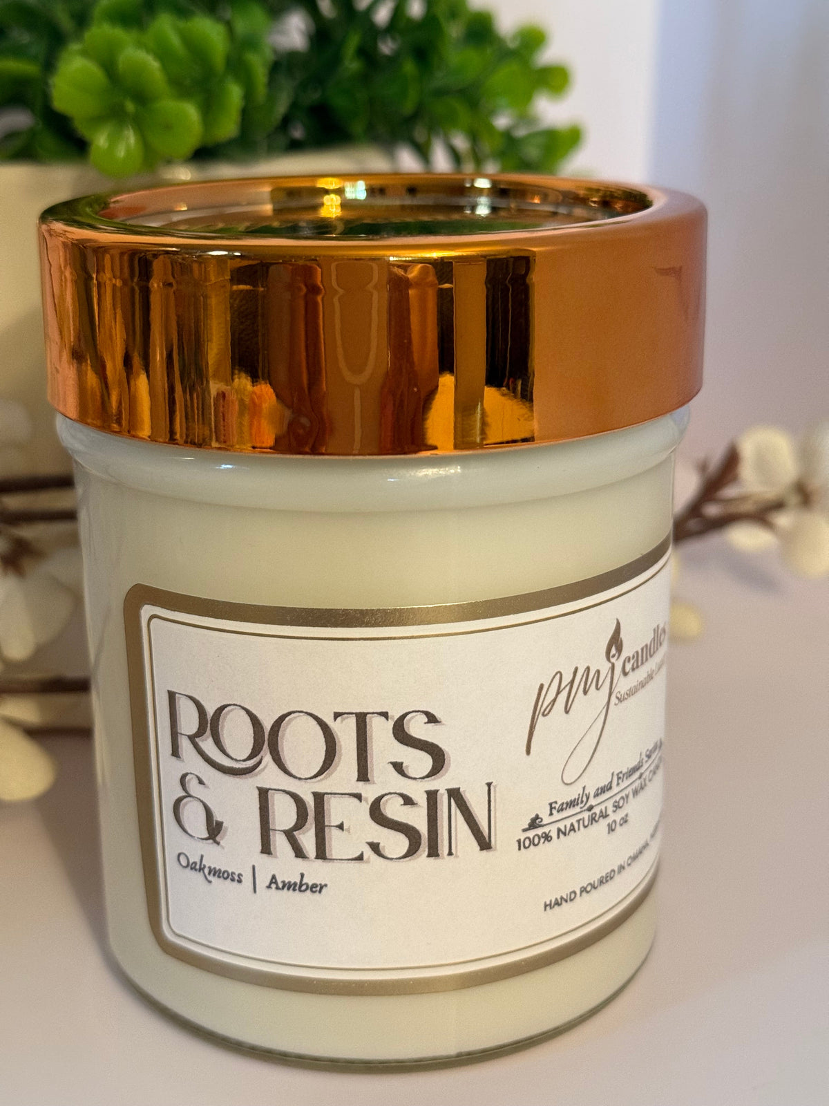 PMJ Candles Roots and Resin soy wax candle in a glass jar with a metallic copper lid and elegant label